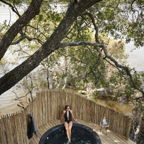 woman seated at a small pool in a deck of an Island treehouse suite at Kandahar Island