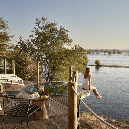 A young woman sitting on a deck over looking Victoria Falls River Lodge
