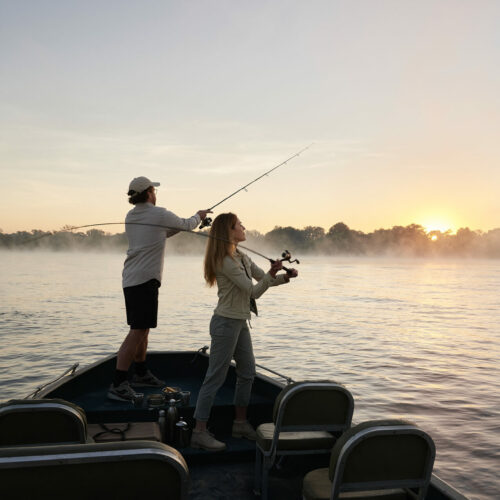 two people casting their fishing rods off a boat into the Zambezi River