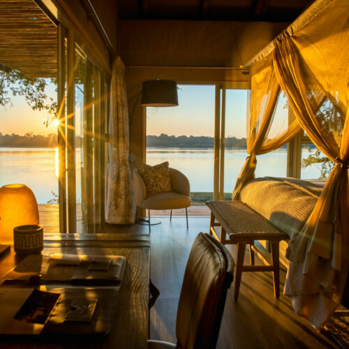 golden sunset from inside the bedroom suite of Victoria Falls River Lodge