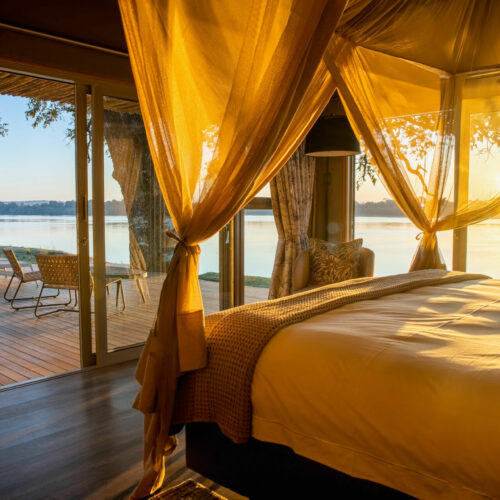 golden sunlight streaming into a bedroom suite overlooking the Zambezi River